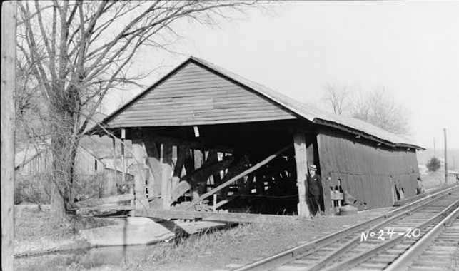 B&W photo of a long, wooden building with a pointed roof.