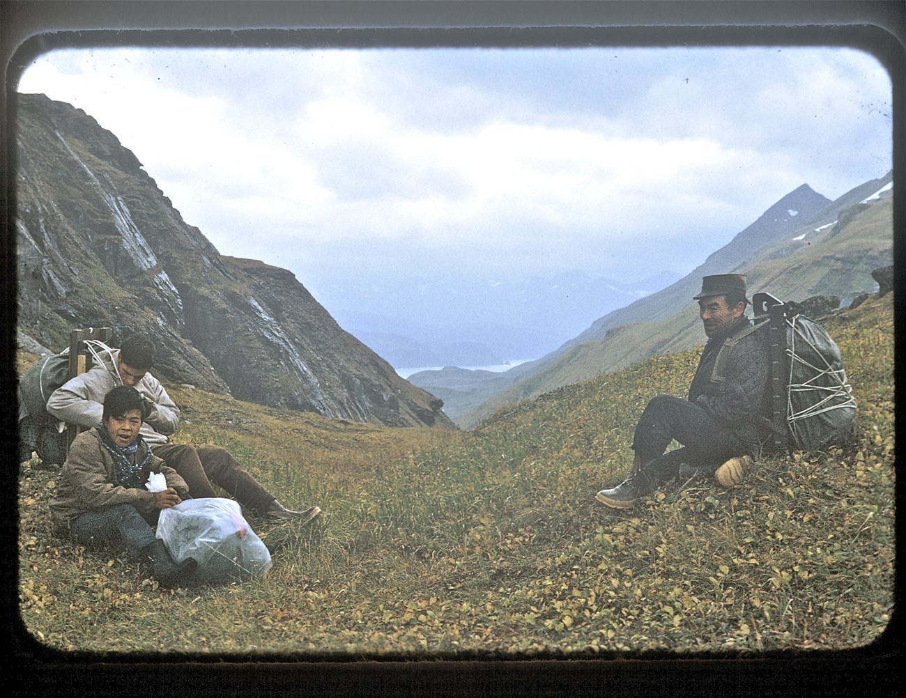 Three people spaced out, in the saddle of a treeless mountain