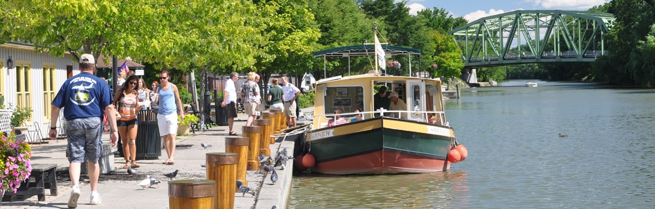 ERIE Pittsford Waterfront People walking next to a canal and canal boat