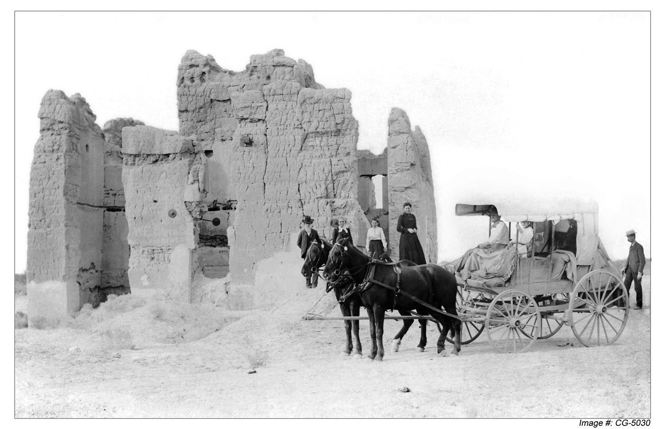 Early Visitors to Casa Grande Ruins Historic black and white photo of visitors in a horse drawn carriage at abode ruins