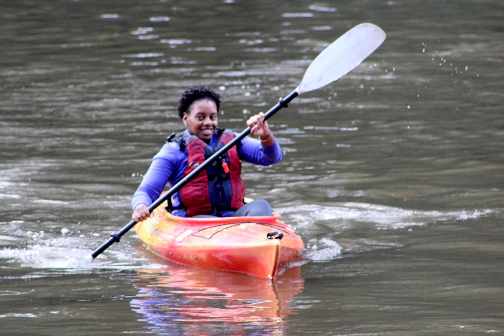 A girl kayaks in a river.