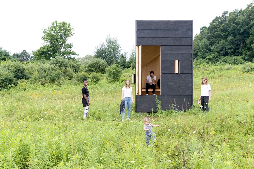 Five people and a mobile writing studio in a meadow.