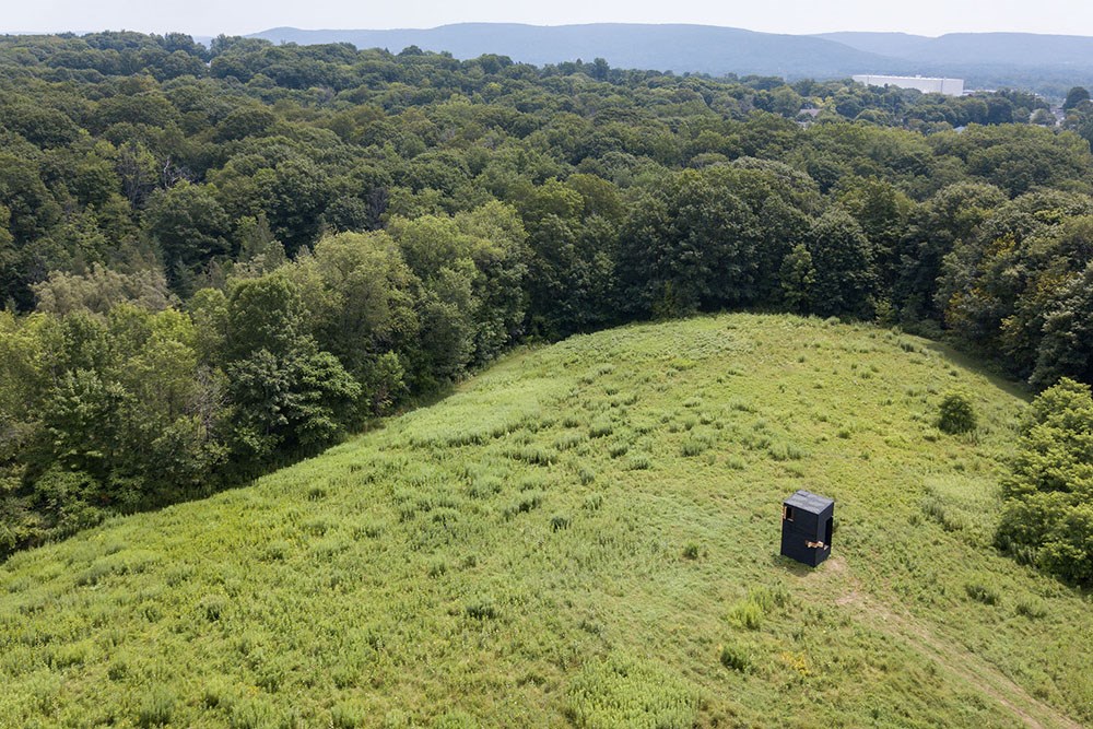 Aerial view of a mobile writing studio in a meadow surrounded by a forest.