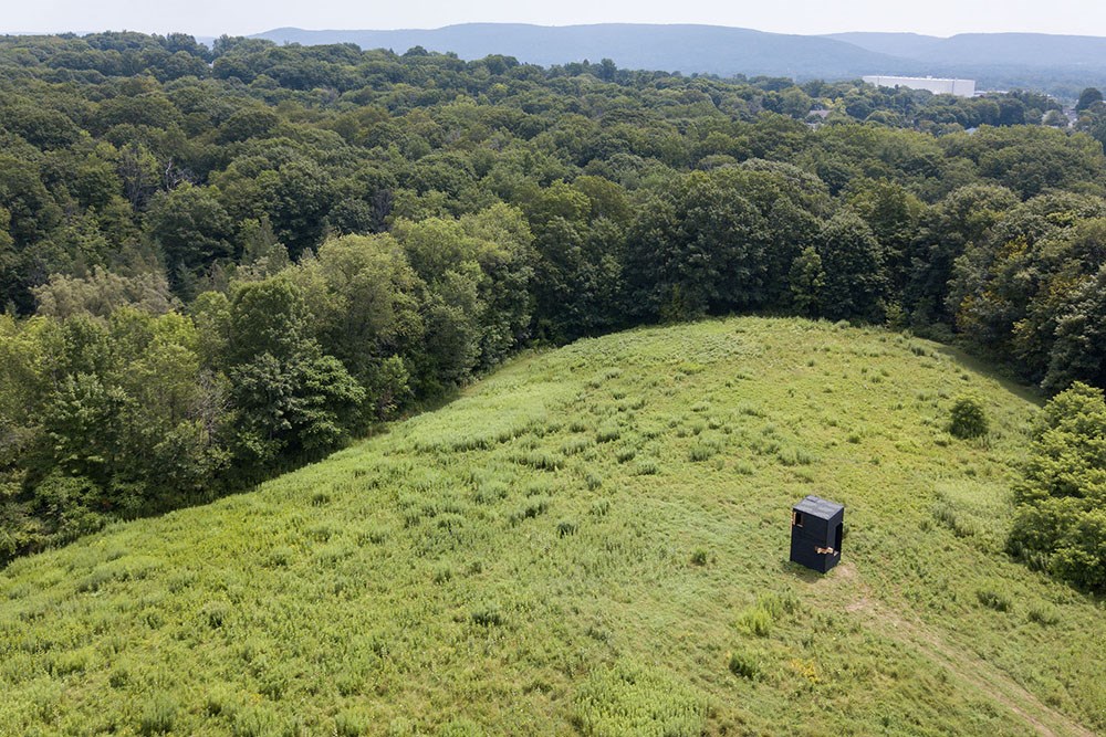 Aerial view of a mobile writing studio in a meadow surrounded by a forest. Aerial view of a mobile writing studio in a meadow surrounded by a forest.