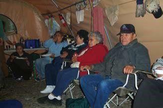 In this recent photo, a group of Alutiiq elders, men and women, sit in a tent together.