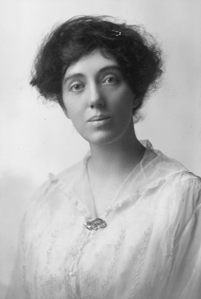 Formal portrait, head and shoulders, Eleanor P. Barker wearing embroidered blouse or dress with brooch.