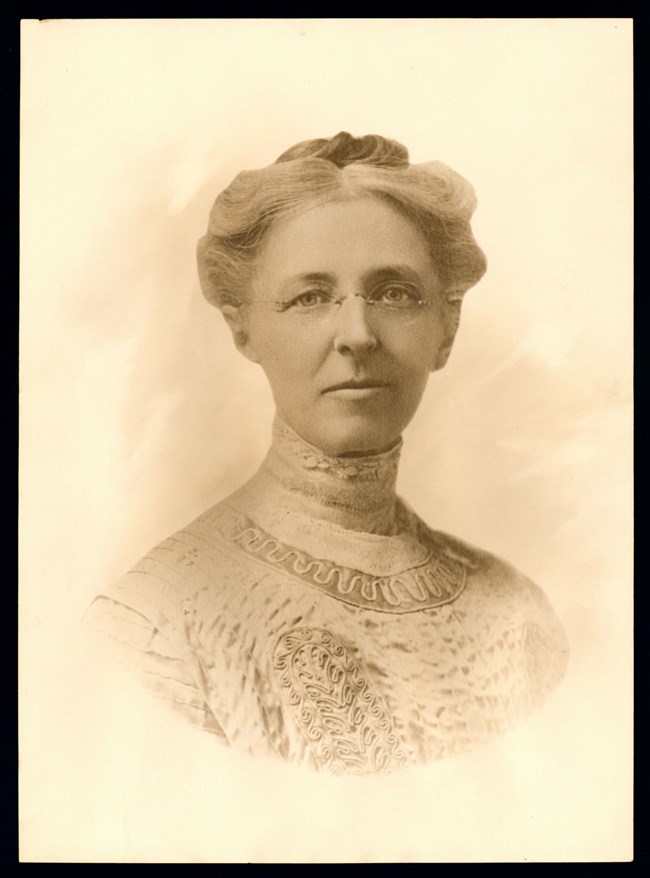 Head and shoulders photograph of Elizabeth Preston Anderson wearing high collar dress and glasses