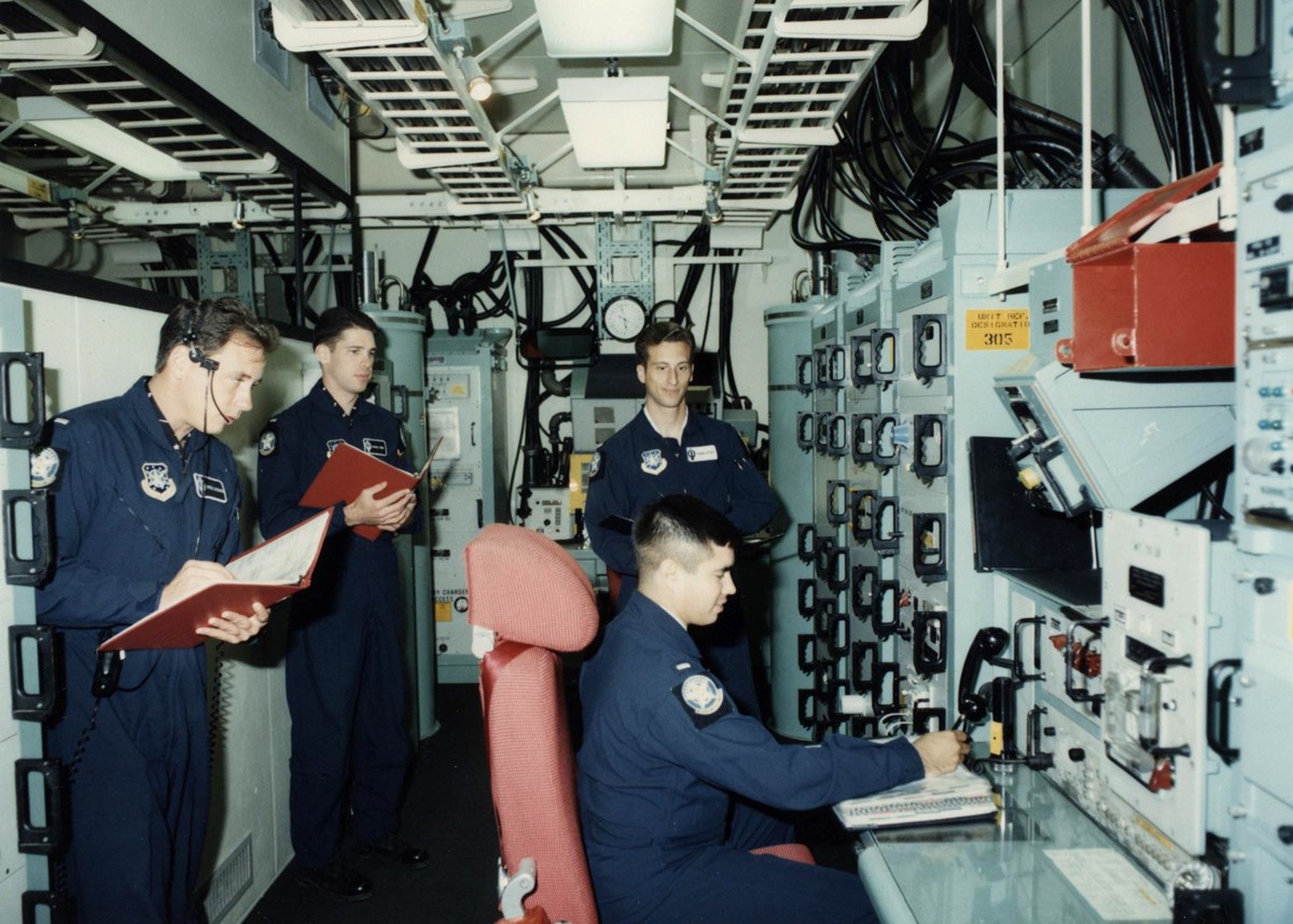 Missileers during an evaluation in the Missile Procedures Trainer at Ellsworth Air Force Base Uniformed officers in a room with electronic consoles