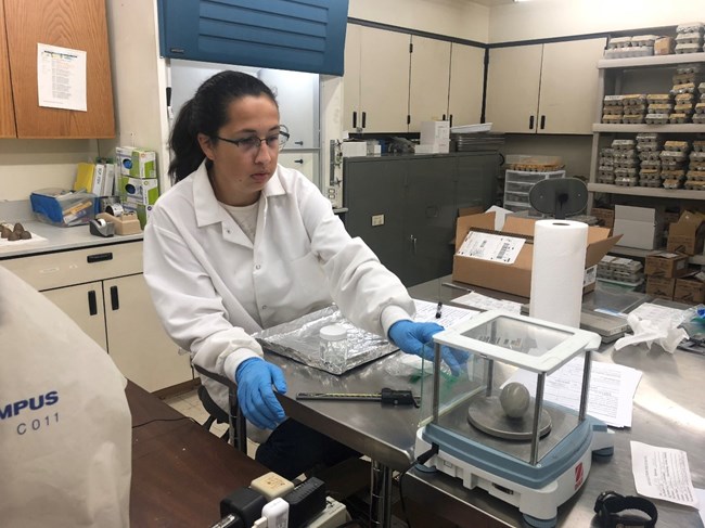 A young woman weighs an egg in a laboratory.