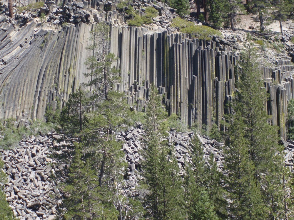 Devils Postpile National Monument Multi-sided column rock formation with trees towering in front.