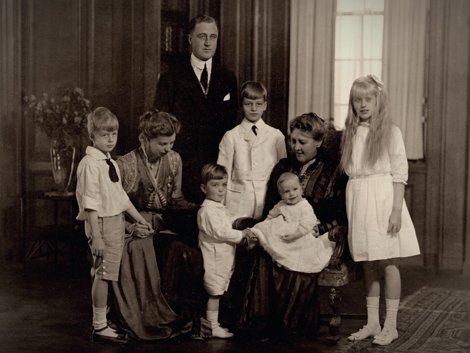 A family of seven posed together near a window.