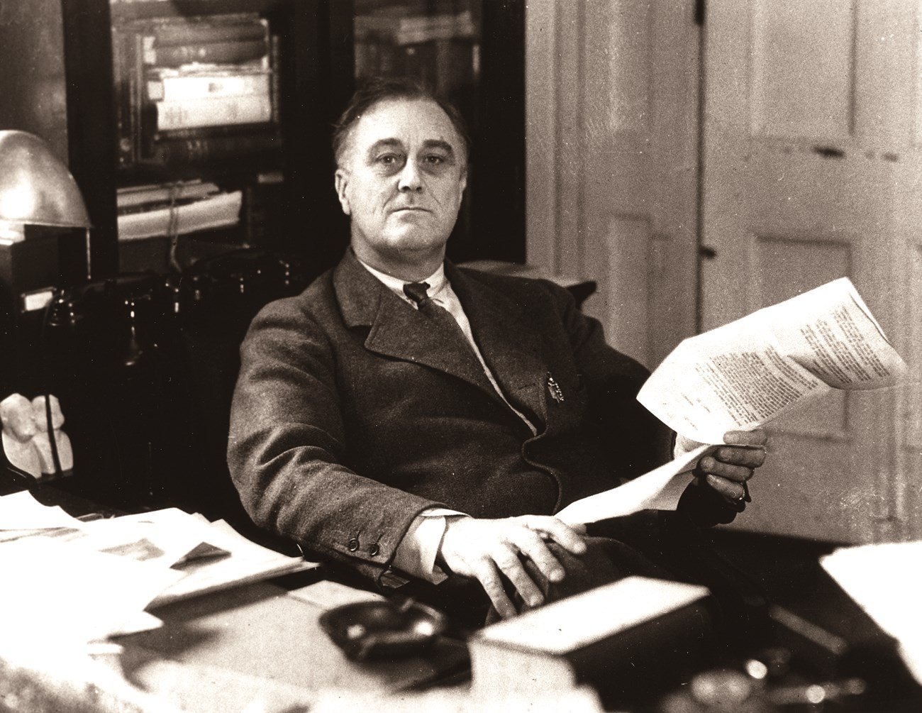 A man sits behind a desk in a small study.