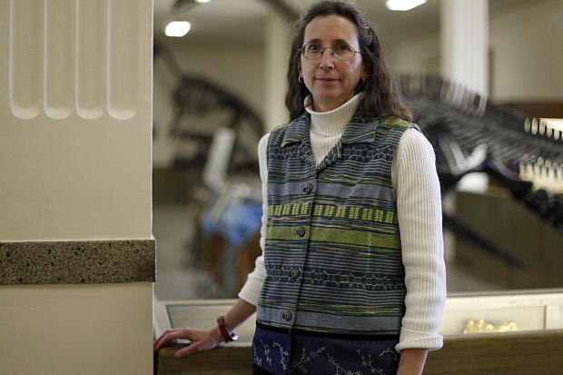 Woman in focus standing in front of an out-of-focus dinosaur skeleton