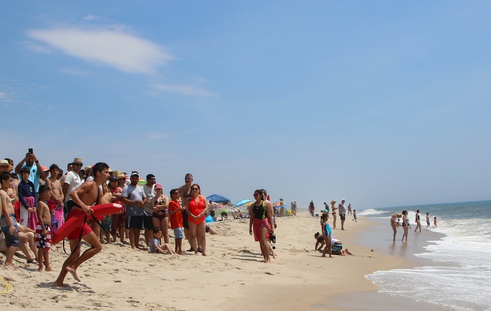 Lifeguard beginning to run toward the water in front of a crowd