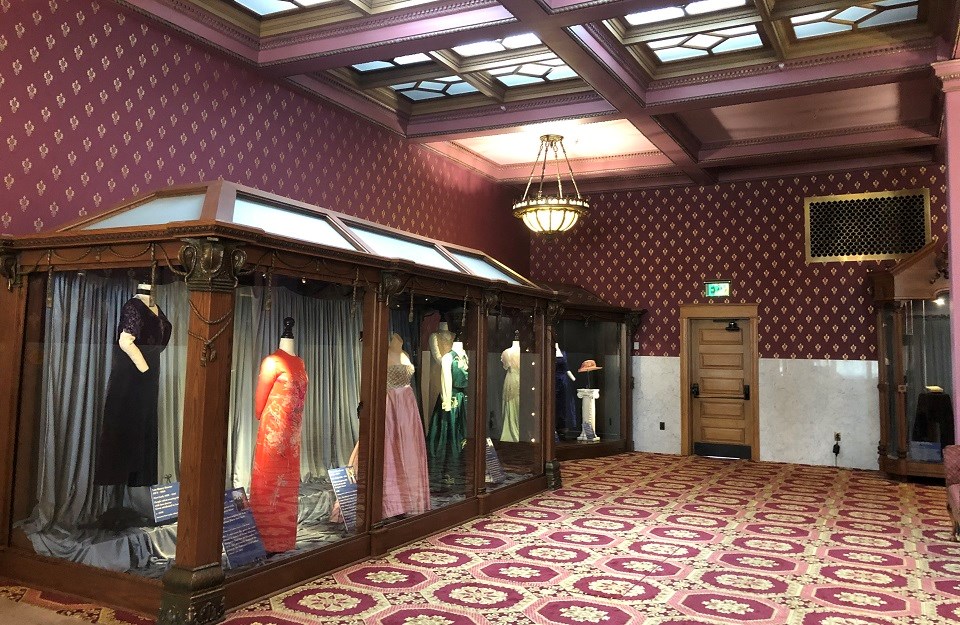 Museum exhibit with a line of historical dresses in glass cases