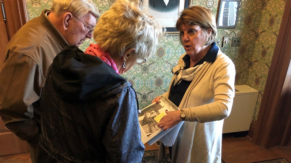 Docent talking to two visitors while showing them a paper