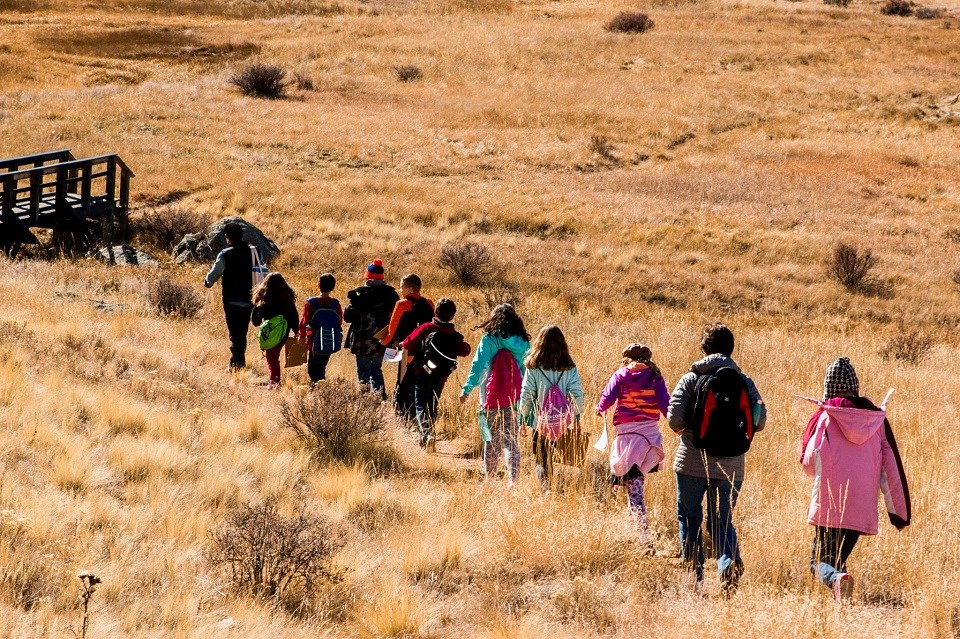 Line of kids hiking through a field