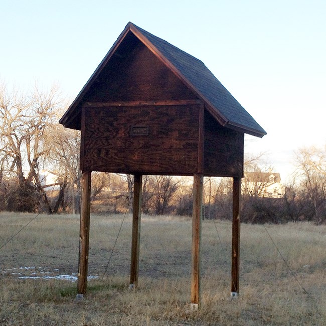 The bat house at Fort Laramie National Historic Site A wooden house-shaped structure on stilts