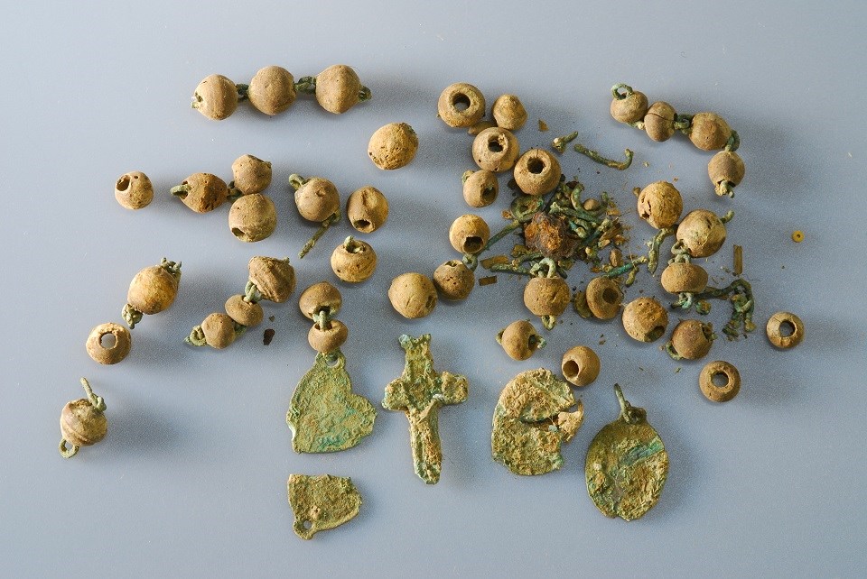 Photo of wooden beads and oxidized metal charms from a rosary.