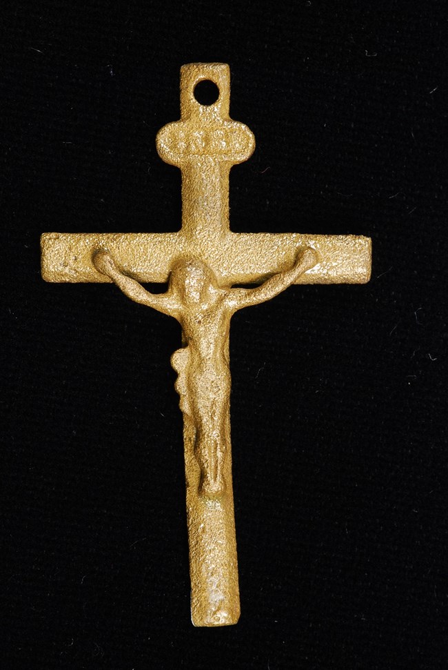 Photo of a small brass-colored crucifix, somewhat worn.