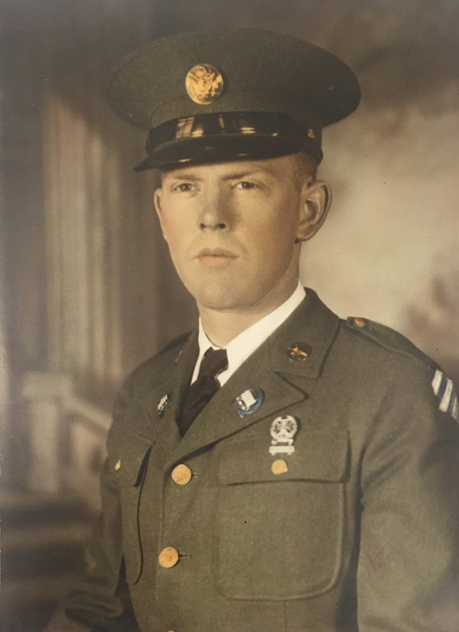 Colorized black and white photo of man in green US Army dress uniform with hat.