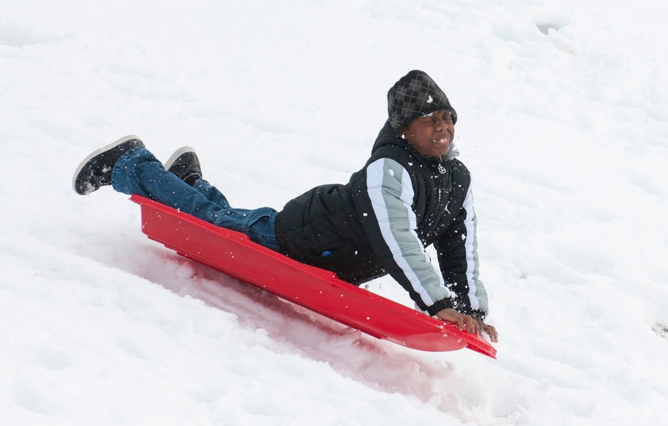 Child sledding down a hill in the snow