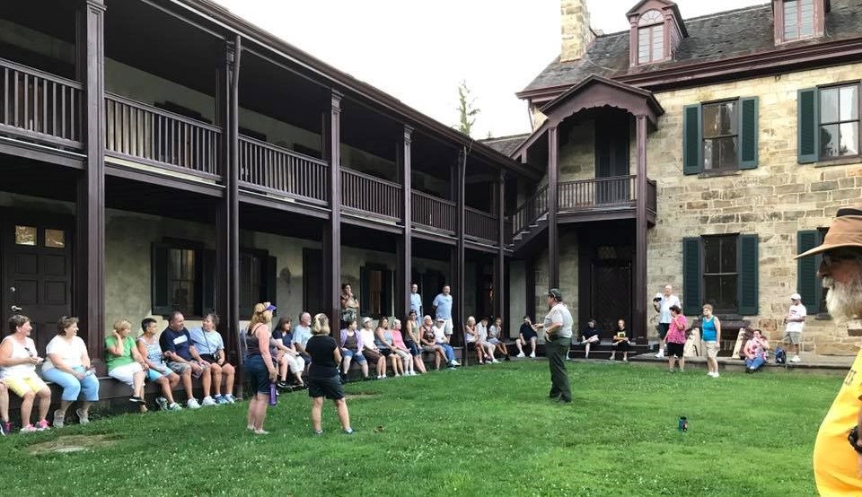 Ranger giving a talk to a crowd sitting outside the Gallatin House