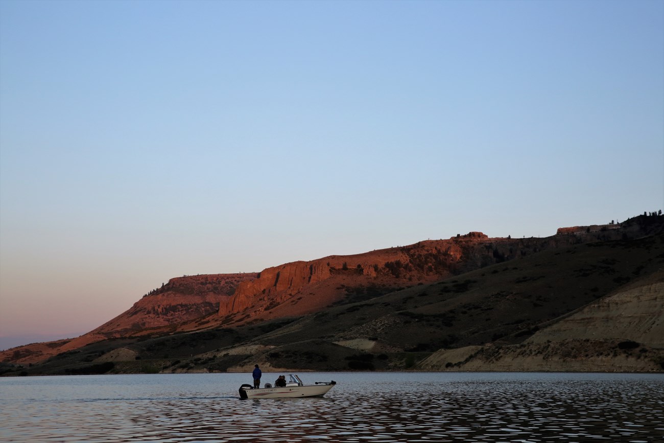 A boat glides across a lake at sunrise.