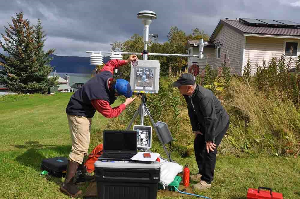 Two scientists install particulate monitoring equipment.