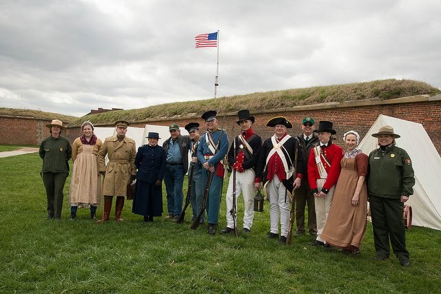 Three park rangers pose with volunteers in period costumes.