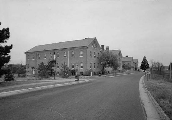 B&W photo of a brick building with a road running in front.