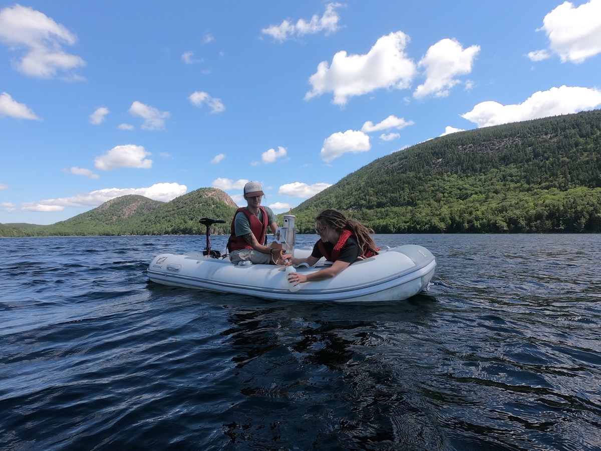 two students in a boat taking water samples from a lake