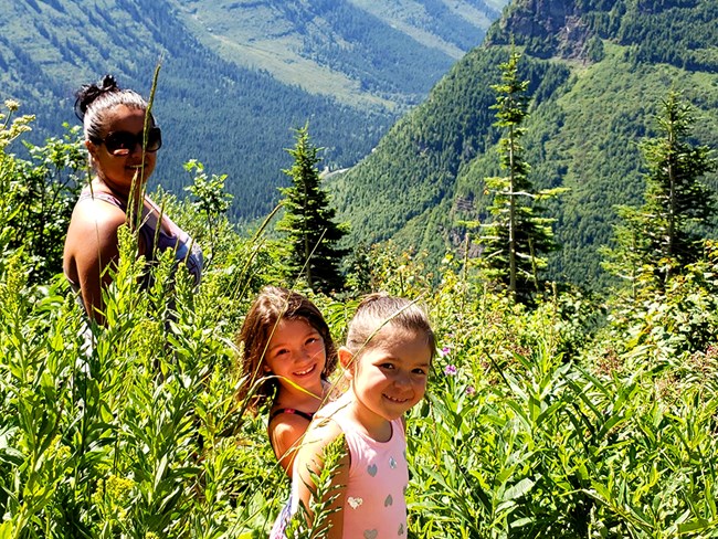 A woman and two children smile in the grass. A woman and two children smile in the grass.