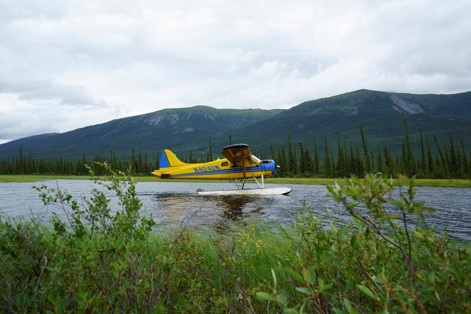 Float plane on a river near a mountain range