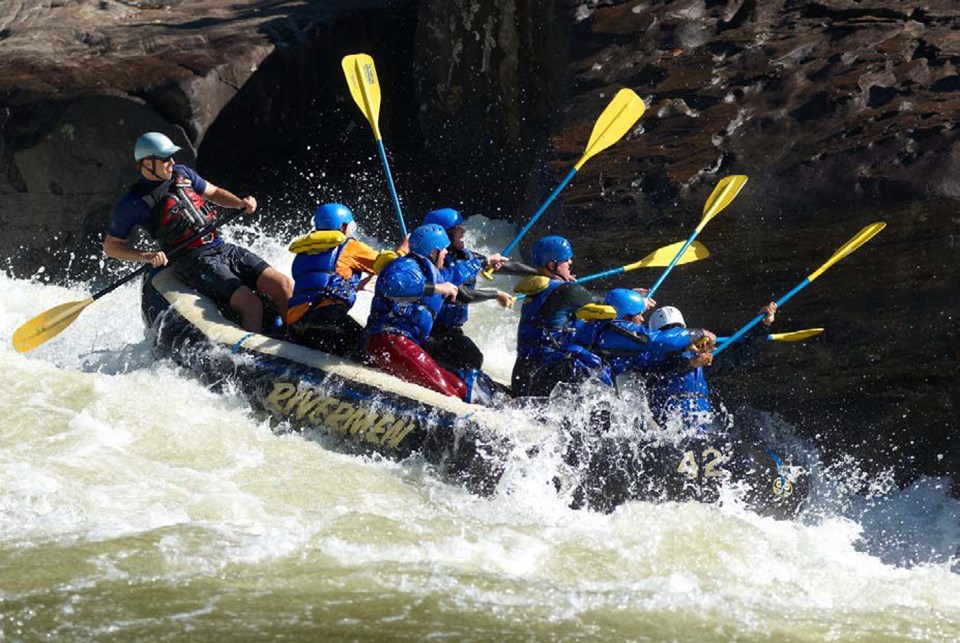 Group of paddlers holding paddles in the air to hit a rock