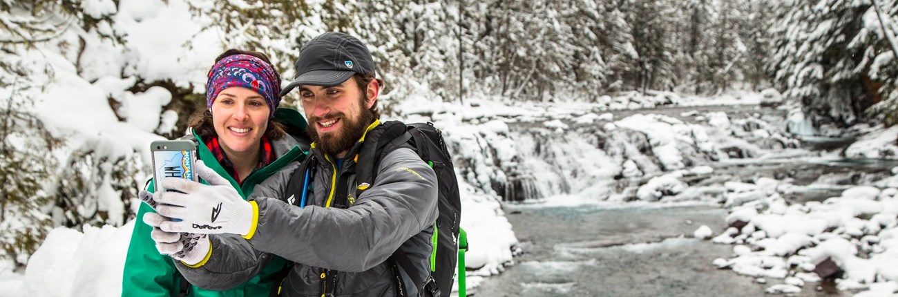 GLAC Sacred Dancing Cascades (NPS Jacob Frank) Two visitors taking a selfie by a frozen creek