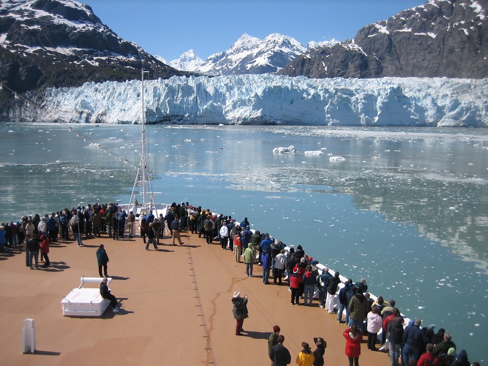 Crowd of people on a cruise ship deck approaching a glacier