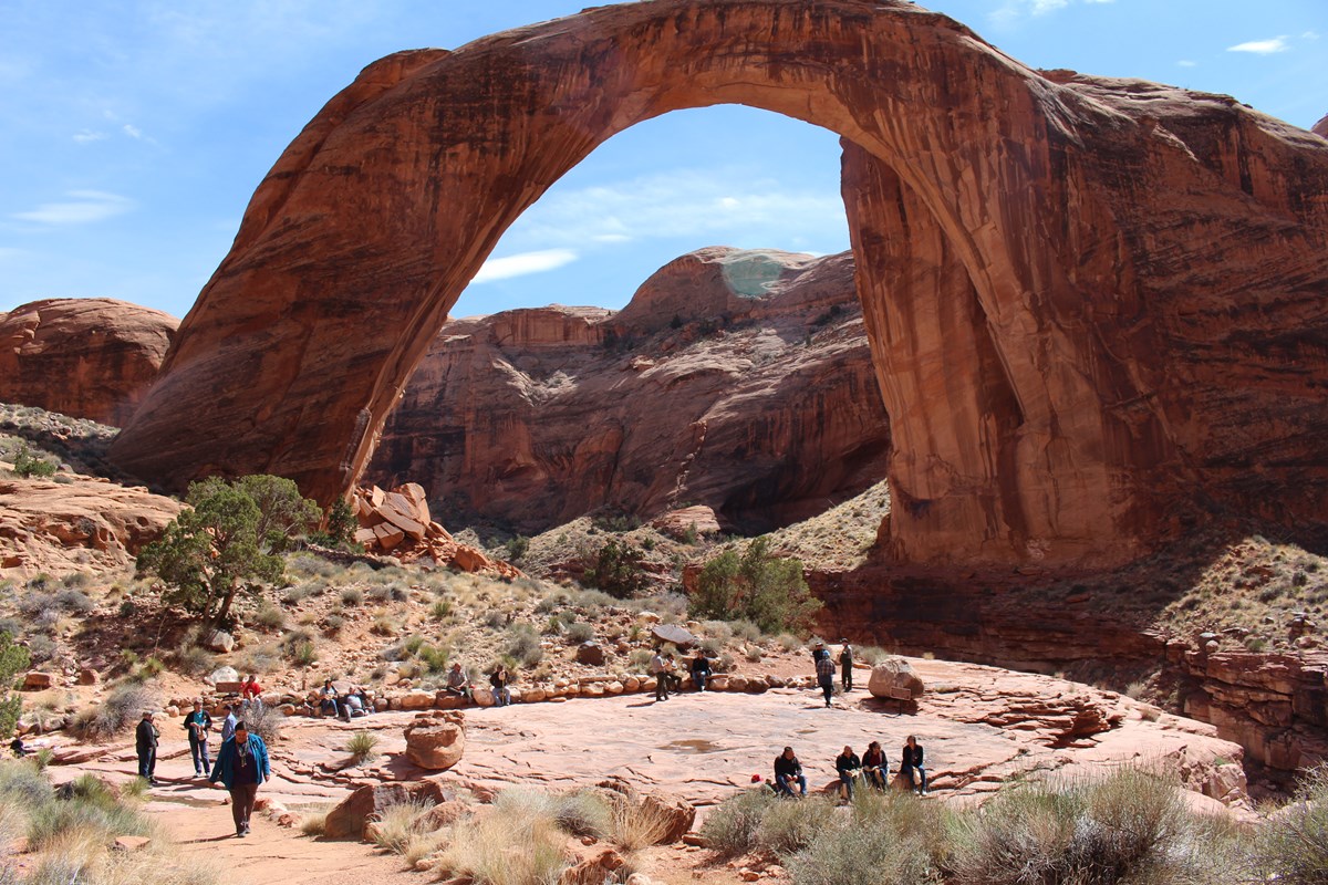 GLCA-RABR air tour gathering_bridge0734_NPS Air tour agreement participants gather with tribal consultants at Rainbow Bridge to experience the unique geological qualities of the iconic arch, and discuss the cultural significance of the bridge and surrounding "Navajo Nation" lands.