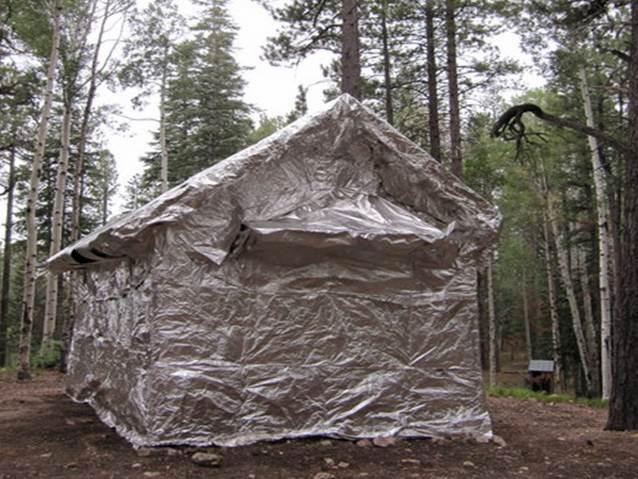 Cabin near forest fully wrapped in silver reflective material.