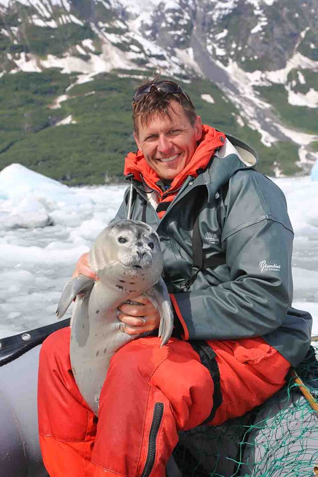 Scott holds a harbor seal pup, as he does research.