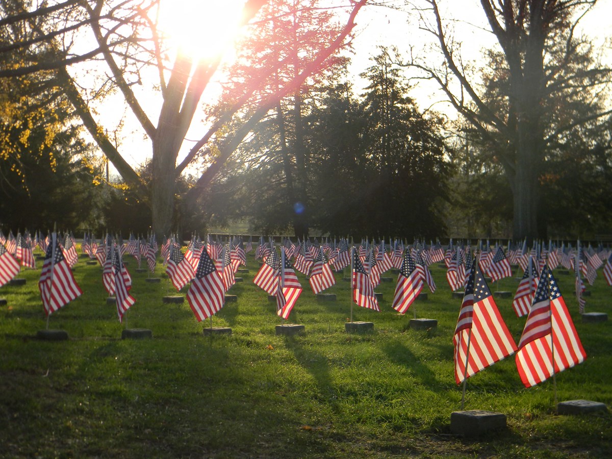Setting sunlight filters through trees and highlights decorated graves
