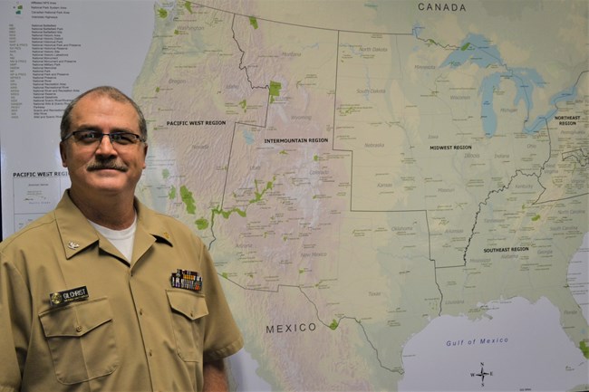 Headshot of Tracy Gilchrist standing in front of a map of the U.S.