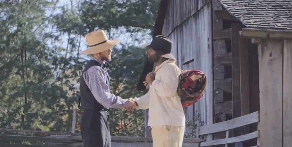 Photo of a two men in period farming clothing shaking hands