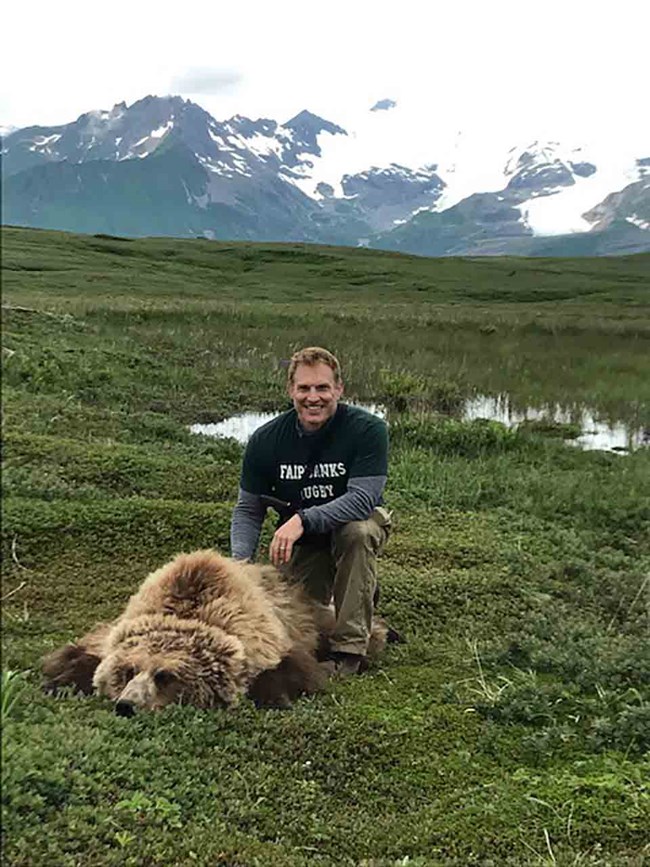 Grant in a green meadow with a tranquilized bear.