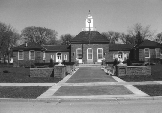 Village Hall, Greendale Historic District B&W photo of a brick building with a small court and flagpole in front.
