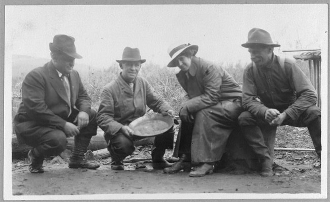 Group Portrait of a women and three men holding a pan with gold in it