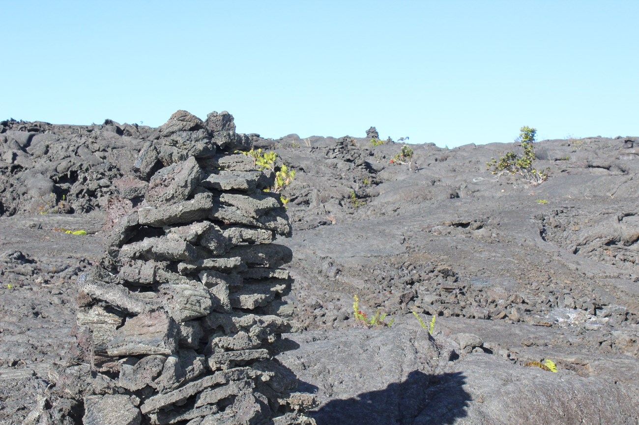 large stack of gray rocks in a cone shape on a lava field