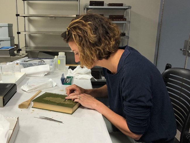 A woman works on the cover of a book.