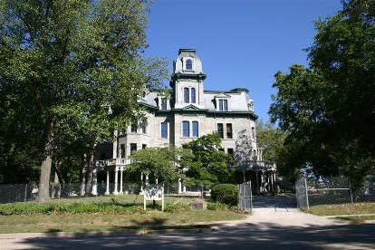 Large grey building with a large porch.