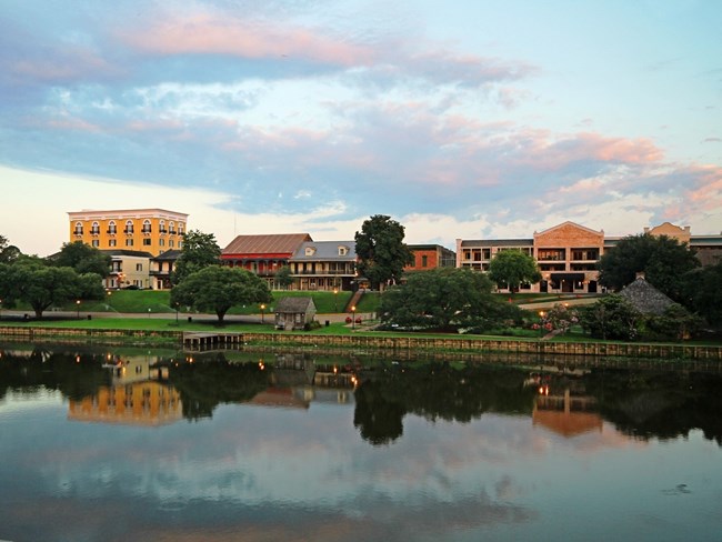 historic buildings, homes and trees reflecting on the river